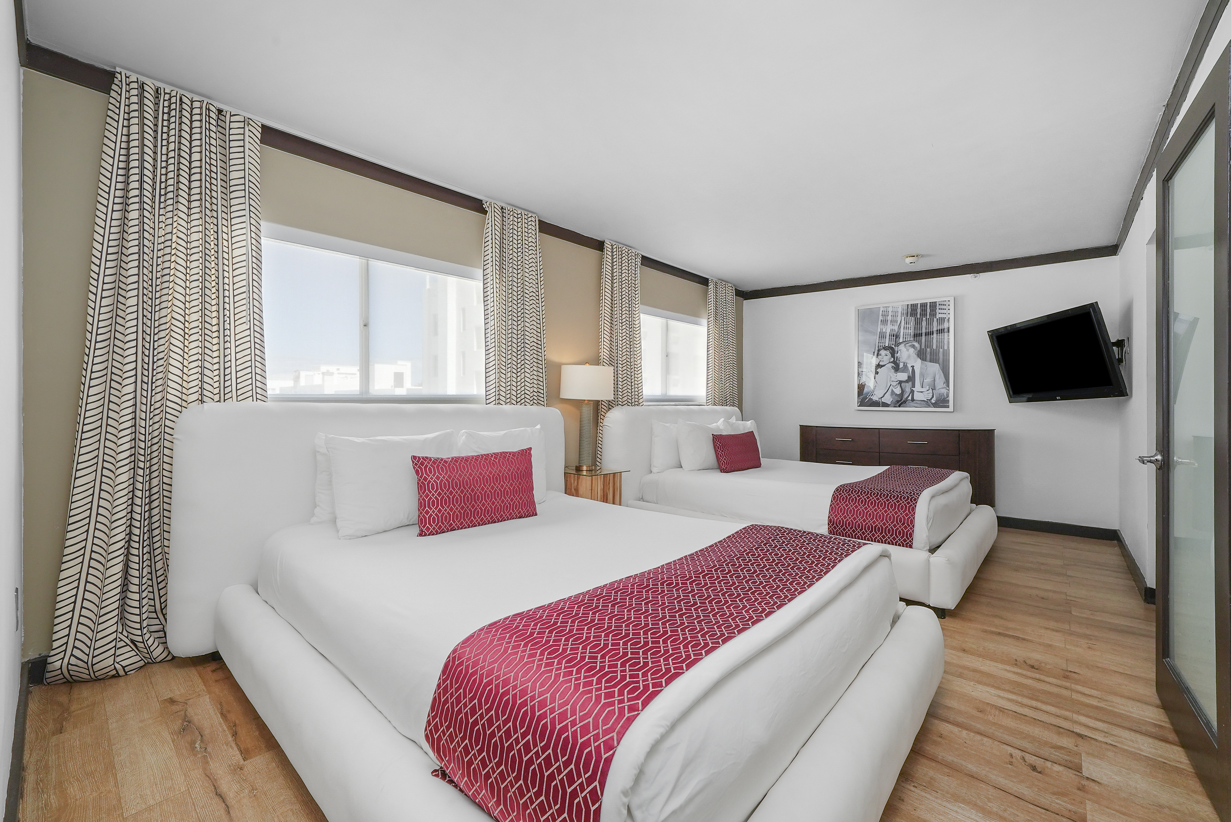 A hotel room with two beds, a TV, and a window.