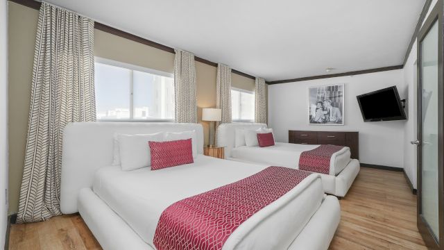 A hotel room with two beds, a TV, and a window.
